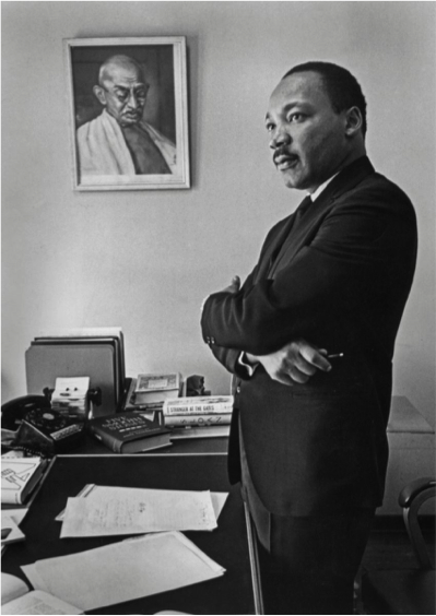  Martin Luther King Jr. stands in his office with a picture of Mahatma Gandhi in the background. 