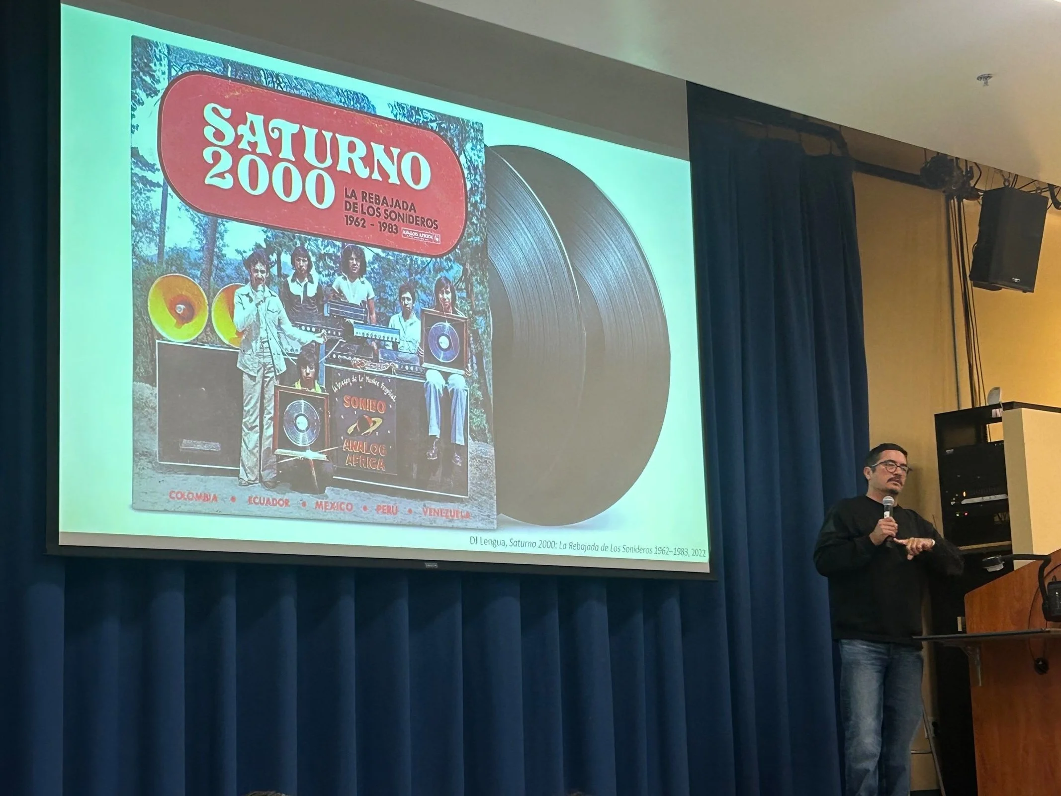  Artist Eamon Ore-Giron tells a UCSB audience about the significance of the “double groove” in his art. Ore-Giron compiled the album  Saturno 2000: La Rebajada de los Sonideros,  using psychedelic music that came from Latin America.  